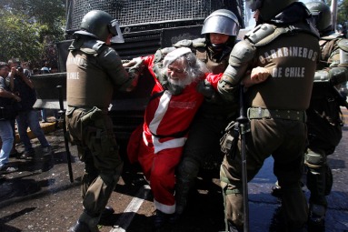 A demonstrator dressed as a Santa Claus is arrested by riot policemen during clashes with students in Santiago